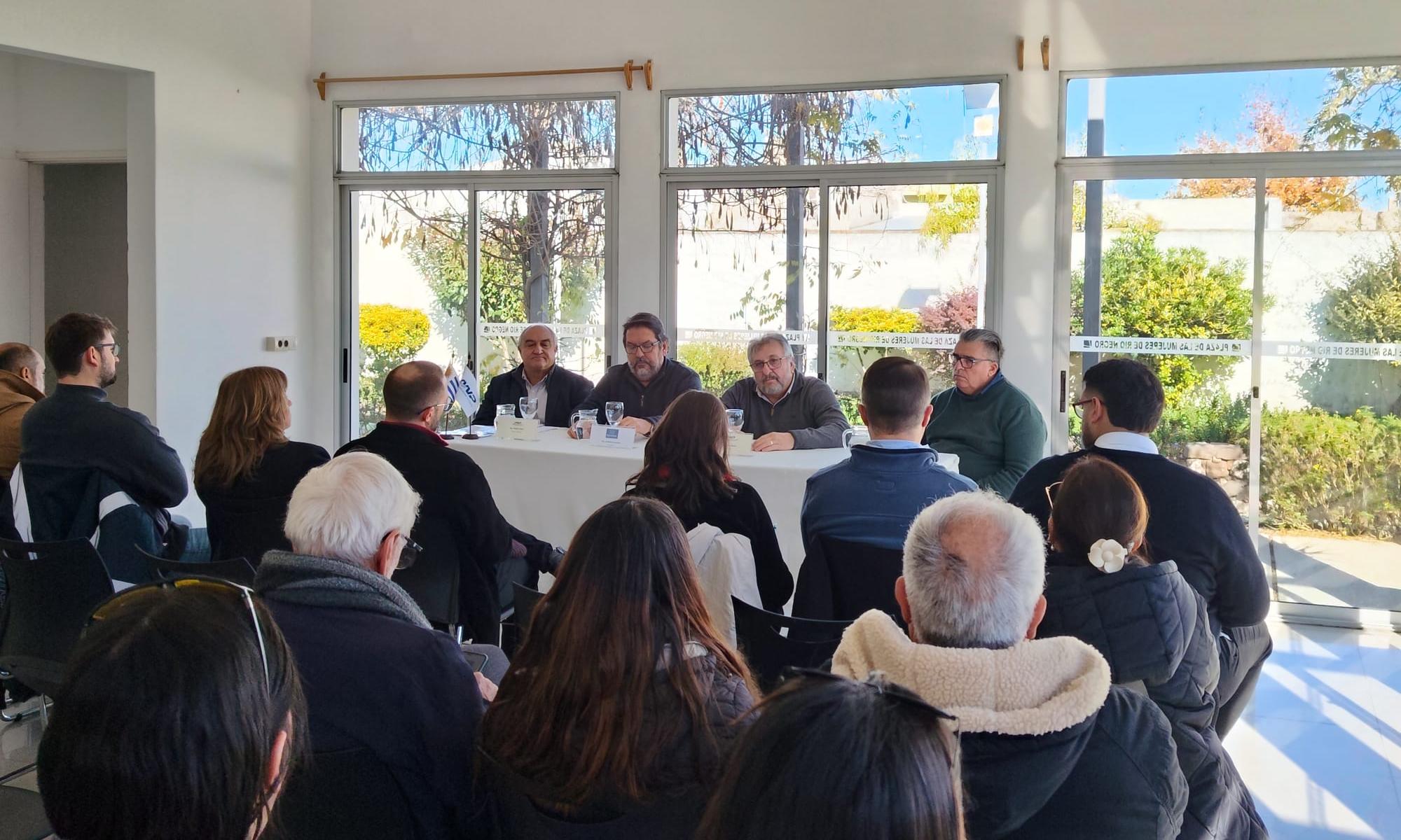 personas sentadas alrededor de una mesa frente a público en sillas