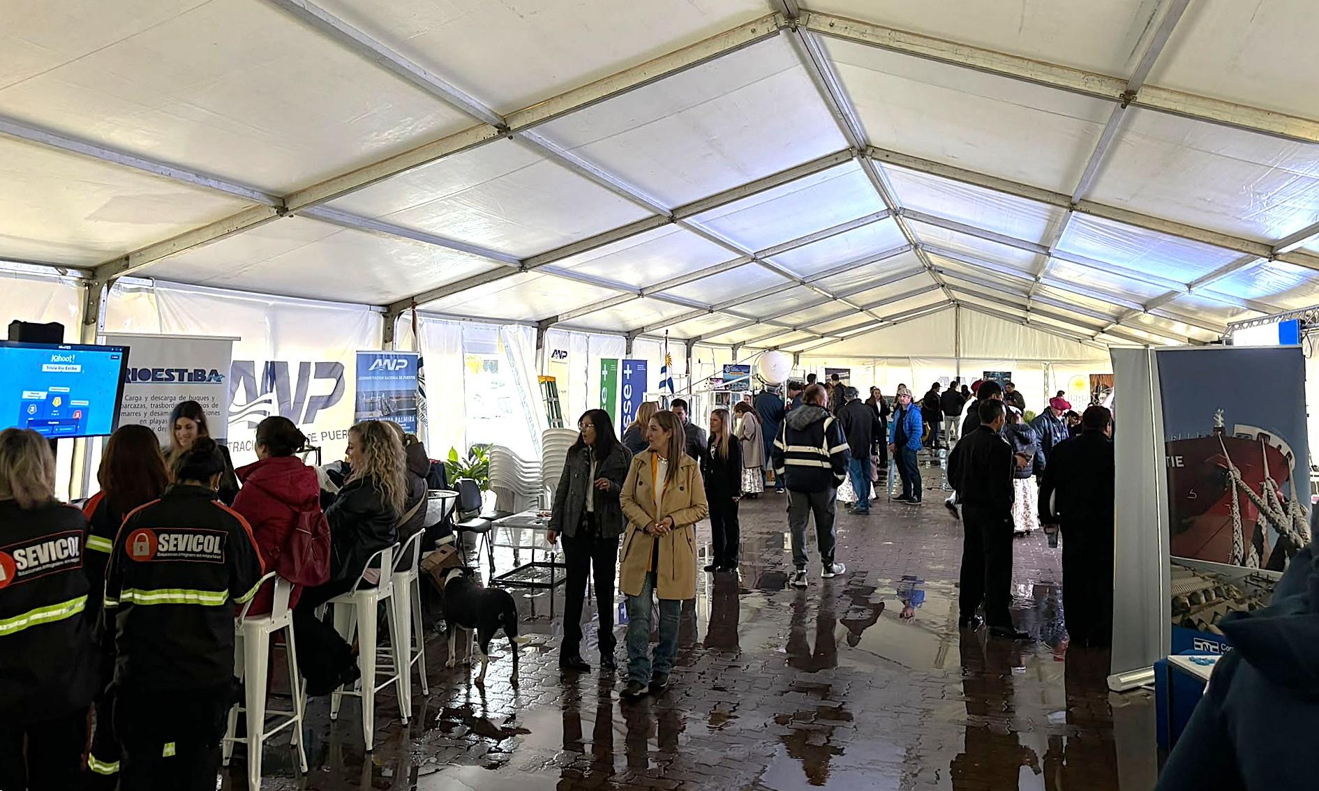 carpa blanca con estands y personas caminando y observando